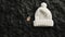 a beautiful white knitted hat beanie, featuring a tag, against a contrasting backdrop of recycled black crumpled paper