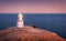 Beautiful white lighthouse on the ocean coastline at sunset. Landscape