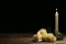 Beautiful white roses and candle on table against black background