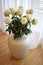 Beautiful white roses in a large white vase on the floor in the room