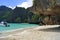 Beautiful white sandy beach beside the blue ocean surrounded by the treed rocks. Thailand.