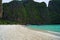 Beautiful white sandy beach beside the blue ocean surrounded by the treed rocks. Thailand.