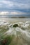 beautiful white and soft wave flow over the rock and mossy hitting the shore.dramatic dark clouds background before storm