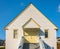 Beautiful white traditional historical house in countryside of Canada. Yellow door and staircase with wood railing