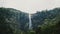 Beautiful wide shot landscape scenery of large jungle waterfall rushing down in wild tropical Sri Lanka forest.