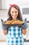Beautiful wife holding a steaming hot tray in the kitchen, holding baked chicken and potatoes in her oven gloves, wearing apron