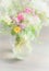 Beautiful wild flowers bunch in glass vase on light background, soft focus, close up.
