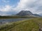 Beautiful wild Lapland nature landscape with blue glacial river, birch tree bushes, snow capped mountains Northern Sweden summer