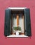 Beautiful window with shutters and a bouquet of daisies in a vase on the windowsill in one of the houses on the island of Burano.