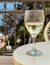 Beautiful wineglass with white wine, standing on the table  against the backdrop of sea. Side view, close-up. Concept of leisure