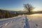 Beautiful winter Christmas landscape. Human footprint track path in crystal white deep snow in empty field, spruce trees forest,