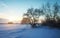 Beautiful winter landscape with frozen lake, trees and sunset