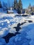 Beautiful winter landscape. Green firs, wooden house covered with snow and frozen river