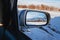 beautiful winter landscape with Tien Shan mountains and trees in field in snow in rearview mirror of car. Concept of