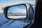 beautiful winter landscape with Tien Shan mountains and trees in field in snow in rearview mirror of car. Concept of