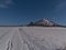 Beautiful winter landscape with tracks on a field covered by snow and butte hill KornbÃ¼hl with chapel Salmendinger Kapelle.