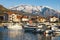 Beautiful winter Mediterranean landscape. Fishing boats in harbor on background of snowy mountain peaks. Montenegro, Tivat city