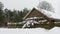 Beautiful winter nature background. Rural landscape with an old barn. Thatched roof barn covered in snow in winter.