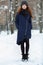 Beautiful winter portrait of young adorable redhead woman in cute knitted hat winter having fun on snowy park path