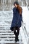 Beautiful winter portrait of young adorable redhead woman in cute knitted hat winter having fun on snowy park stairway