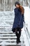 Beautiful winter portrait of young adorable redhead woman in cute knitted hat winter having fun on snowy park stairway