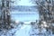 A beautiful winter scenery at the forest lake: a snowy foot bridge and dark trees