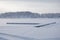 Beautiful winter specific photo. Frozen lake at wintertime. Photo with beautiful forest in the background and a dock lying in the