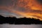 Beautiful winter sunset with orange cloud sky and snow Alps mountains and forest in Engadine region