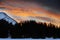 Beautiful winter sunset with orange cloud sky and snow Alps mountains and forest in Engadine region