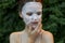 Beautiful woman anti-aging mask touch your face with your hand in nature bare shoulders