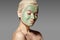 Beautiful Woman Applying Green Facial Mask. Beauty Treatments. Spa Girl Apply Clay Facial mask on grey background