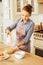 Beautiful woman in apron smiling while mixing liquid dough for baking using an electric mixer