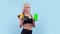 Beautiful woman with an athletic body holds plate of fruit and phone with an app, green screen. Muscular woman shows