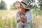Beautiful woman in a big hat enjoing the sun on a field with flowers. Summer lifestyle. Outdoor