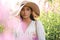 Beautiful woman in a big hat enjoing the sun on a field with flowers. Summer lifestyle. Outdoor