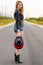 Beautiful woman biker standing on the road with a motorcycle helmet in hand