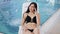 Beautiful woman in bikini posing near the swimming pool. Portrait of fashion model girl in swimsuit lying on the