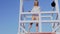 Beautiful woman in bikini standing at the lifeguard station, lifeguard tower.