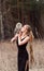 Beautiful woman in a black dress with an owl on his arm. Blonde with long hair in nature holding a owl. Romantic delicate girl