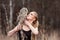 Beautiful woman in a black dress with an owl on his arm. Blonde with long hair in nature holding a owl. Romantic delicate girl