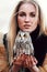 Beautiful woman in a black dress with an owl on his arm. Blonde with long hair in nature holding a owl. Romantic delicate girl