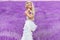 Beautiful woman with blond hair in a beautiful long white wedding dress stands on a field with heather flowers