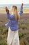 Beautiful woman with blond hair in elegant clothes and accessories posing in flowering lavender field