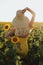 Beautiful woman with blond hair in elegant dress posing in flowering sunflower field