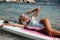 Beautiful woman with blond hair in elegant swimming suit posing with surfer board in the sea