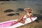 Beautiful woman with blond hair in elegant swimming suit posing with surfer board in the sea