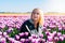 Beautiful Woman with blond hair standing in colorful tulip flower fields in Amsterdam region, Holland, Netherlands