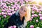 Beautiful Woman with blond hair standing in colorful tulip flower fields in Amsterdam region, Holland, Netherlands