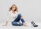 Beautiful woman blonde curly hair jeans fashion full length sitting on floor.