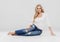 Beautiful woman blonde curly hair jeans fashion full length sitting on floor.